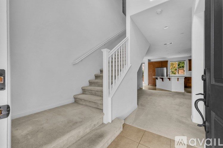 A staircase with a carpeted runner leads to a landing with a table and chairs.