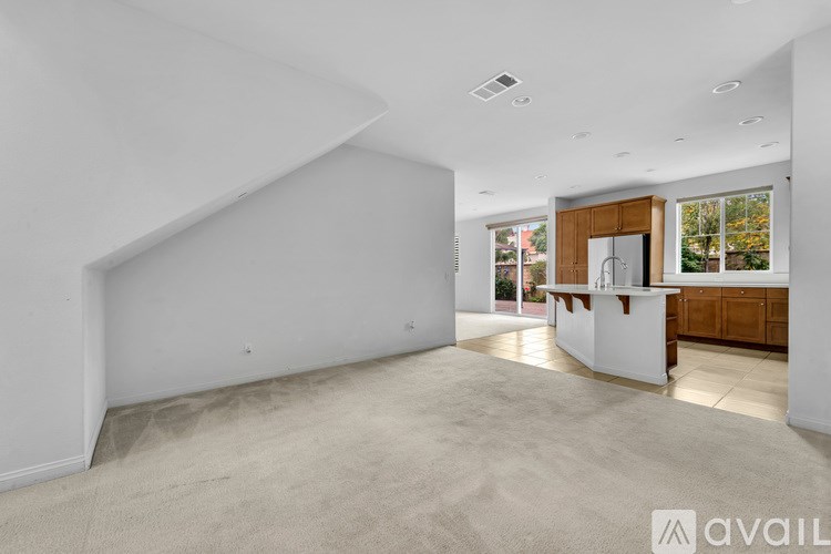 A spacious, empty room with a kitchen area in the background.
