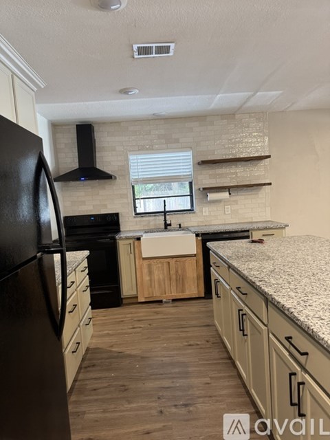 A kitchen with a black refrigerator and wooden cabinets.