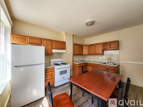 A kitchen with a white fridge, wooden table and chairs, and a white stove.