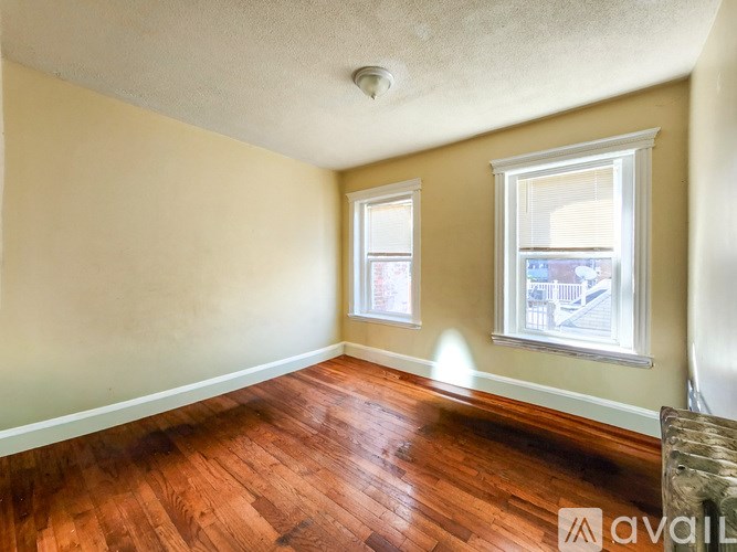 A room with wooden floors and two windows.