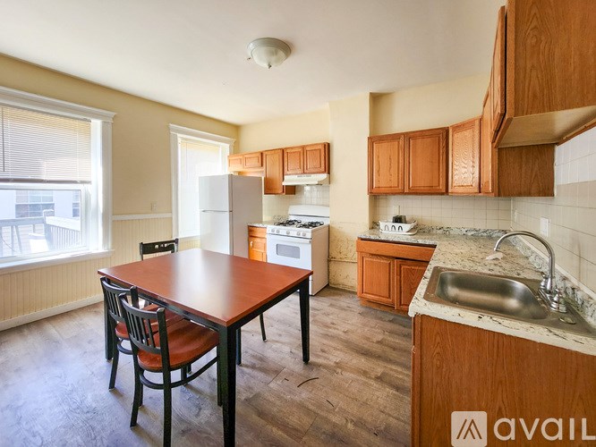 A kitchen with a table and chairs in the foreground and a refrigerator, oven, and sink in the background.