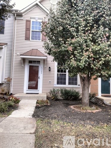 A house with a brown door and a tree in front.