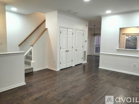 A spacious room with wood flooring and white walls.