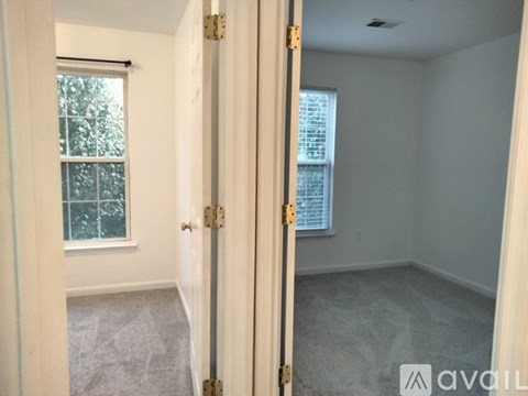 A room with a carpeted floor and a window with blinds.