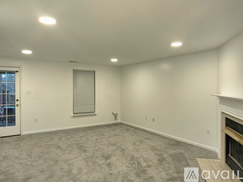 A spacious room with a fireplace and a window with blinds.