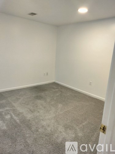 A room with a carpeted floor and a door on the right side.