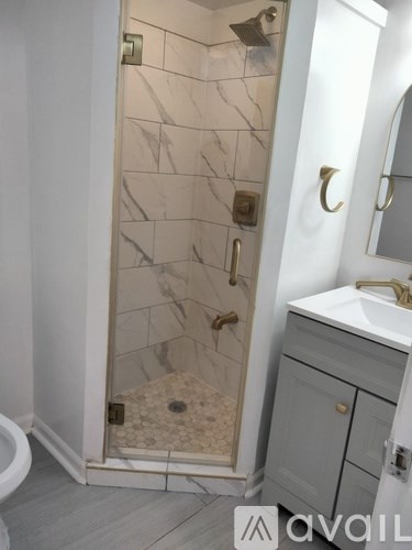 A bathroom with a marble tile shower and a white sink.