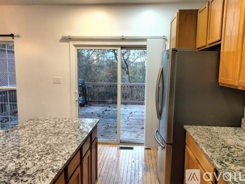 A kitchen with a granite countertop and wooden cabinets.