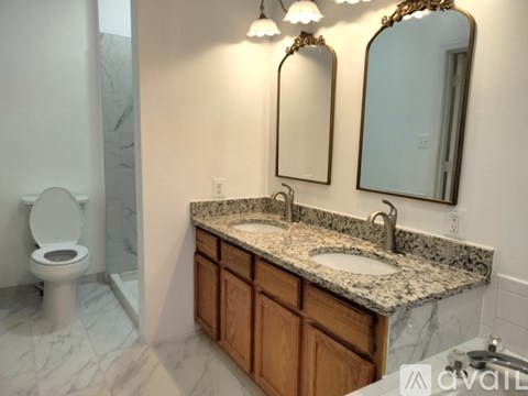 A bathroom with a granite countertop and a white toilet.
