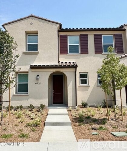 A beige house with a red door and windows.