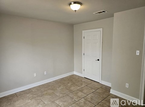 A room with a white door and tiled floor.