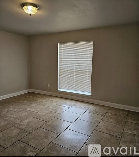 A room with tiled flooring and a window with blinds.