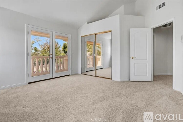 A spacious room with carpeted floor, two sliding glass doors, and a white door.
