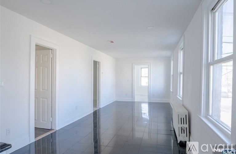 A long empty room with a black floor and white walls.