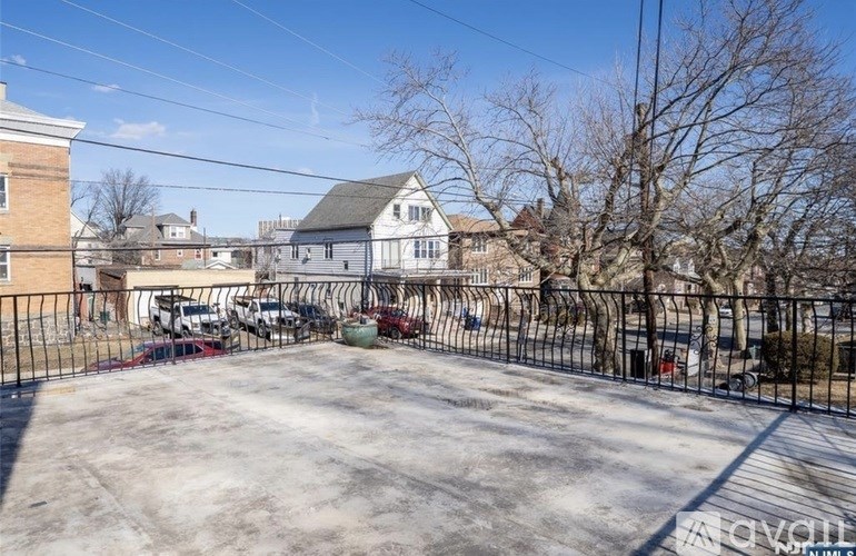 A parking lot with cars and a house in the background.