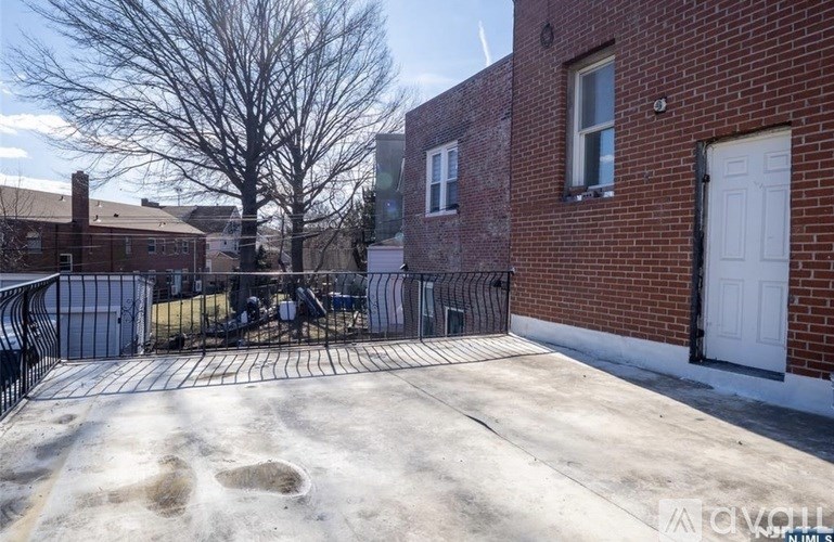 A backyard with a white fence and a brick building.
