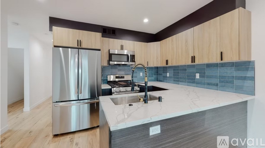 A kitchen with a stainless steel refrigerator, a microwave, and a sink.