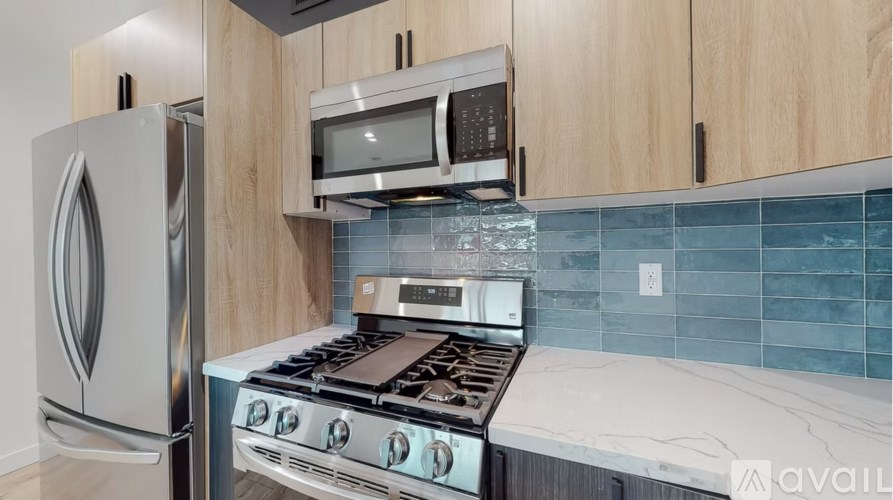 A kitchen with a stainless steel refrigerator, a microwave, and a stove top oven.