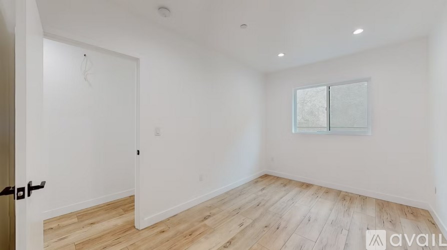 A room with wooden flooring and a window with blinds.