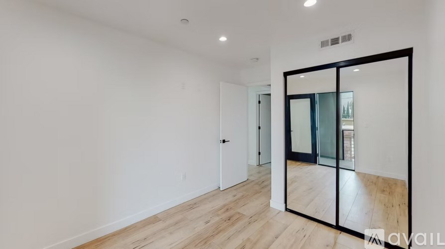 A room with a wooden floor and a large mirror on the wall.