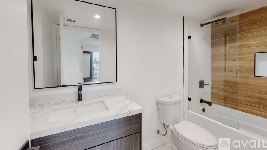 A bathroom with a sink, toilet, and mirror.
