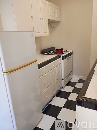 A white fridge and oven in a kitchen with a black and white checkered floor.