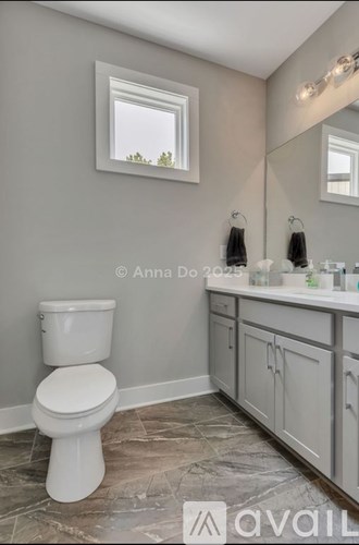 A bathroom with a toilet, sink, and a window.
