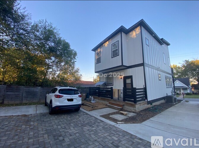 A white house with a black roof and a car parked in front.