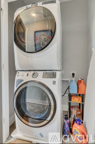 A white washing machine with the door open and a shelf with cleaning products.