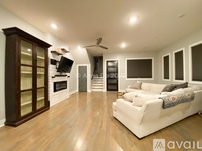 A spacious living room with a white couch and wooden floors.
