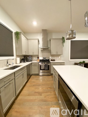 A modern kitchen with wooden floors and stainless steel appliances.