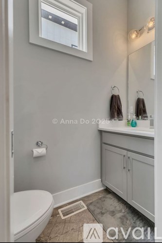 A bathroom with a toilet, sink, and mirror.