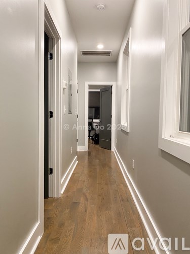 A long hallway with wood floors and white walls.