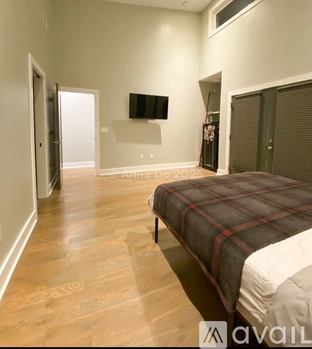 A bedroom with a bed, a flat screen TV, and a wooden floor.