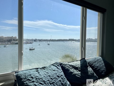 A bedroom with a large window overlooking a body of water with boats.