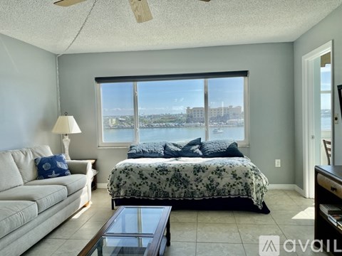 A bedroom with a large bed, a couch, and a window overlooking a cityscape.