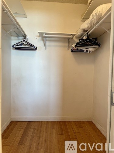 A white closet with clothes hanging on a rail.