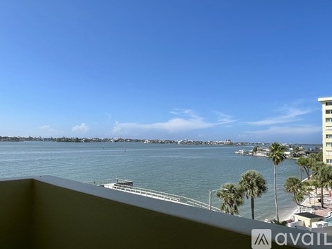 A view from a balcony overlooking a body of water with palm trees and buildings in the distance.