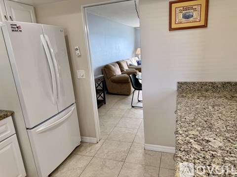 A white fridge in a kitchen with a marble counter.