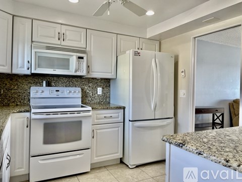 A kitchen with white appliances and cabinets.