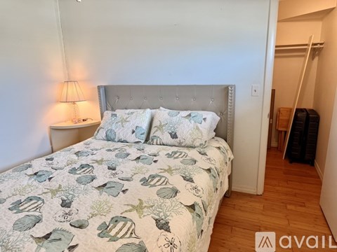 A bed with a white headboard and a green and white patterned comforter.