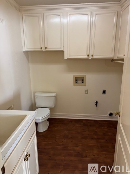 A white toilet sits under a cabinet in a small bathroom.