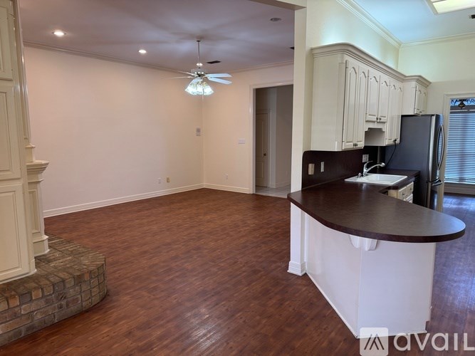 A kitchen with a black fridge and brown flooring.