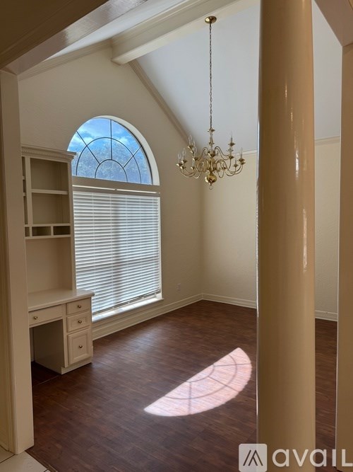 A room with a desk and a chandelier.