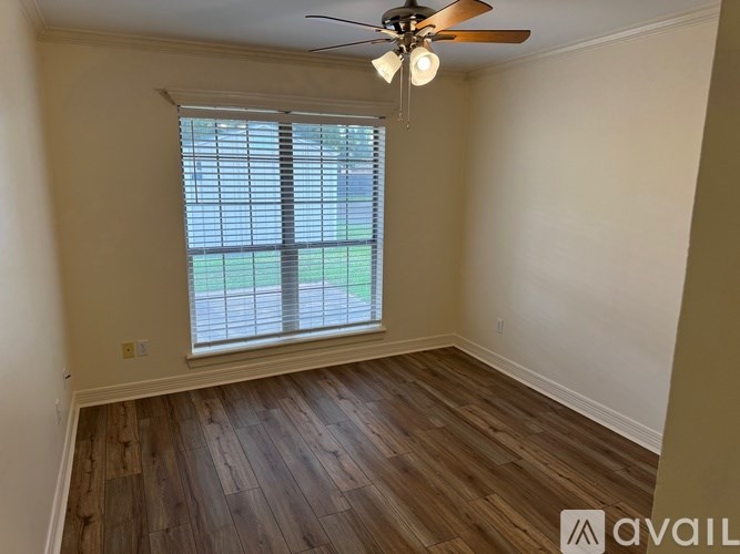 A room with a ceiling fan and a window with blinds.