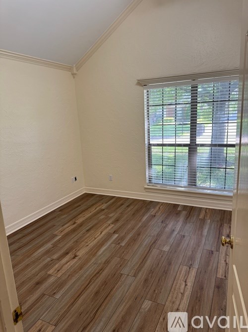 A room with wooden flooring and a window with blinds.