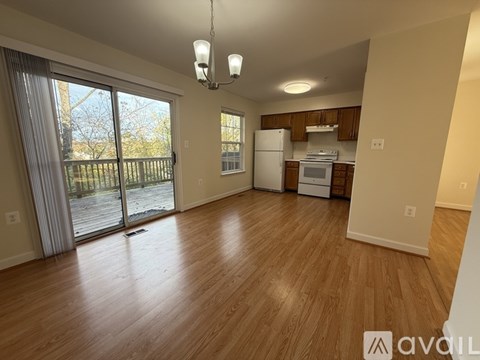 A living room with wooden floors and a kitchen area in the background.