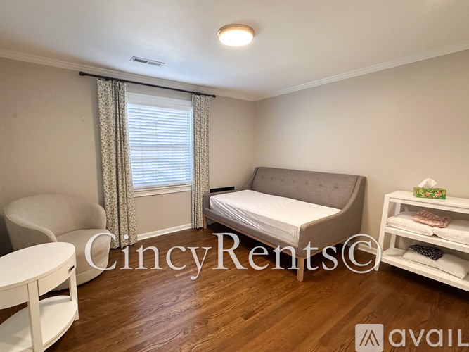 A bedroom with a bed, chair, and window with curtains.