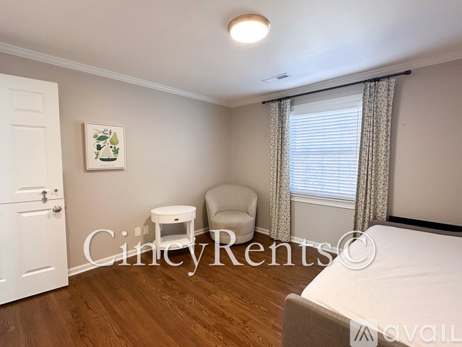 A bedroom with a bed, chair, and window with curtains.